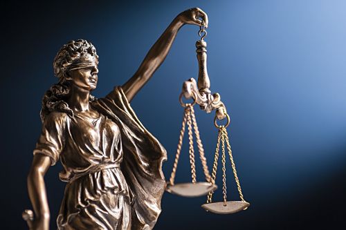 Bronze figurine of Lady Justice with her scales Bronze figurine of a blindfolded Lady Justice with her scales representing law and order on a blue background with copy space