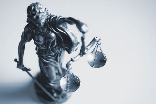 Top down view of a statue of Justice Top down view of a statue of Justice wearing a blindfold and holding a sword and the scales of Justice in a law enforcement, judicial and judgement concept over white with copy space