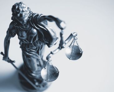 Top down view of a statue of Justice wearing a blindfold and holding a sword and the scales of Justice in a law enforcement, judicial and judgement concept over white with copy space